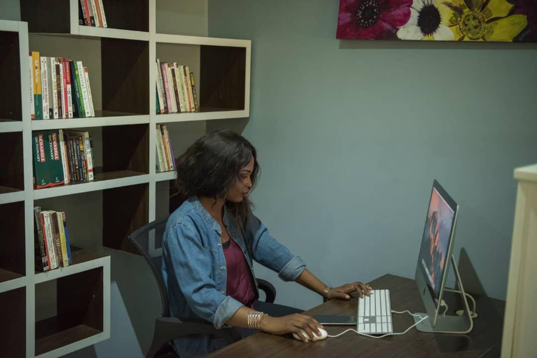 A woman reading a book at a wooden desk in warm daylight
