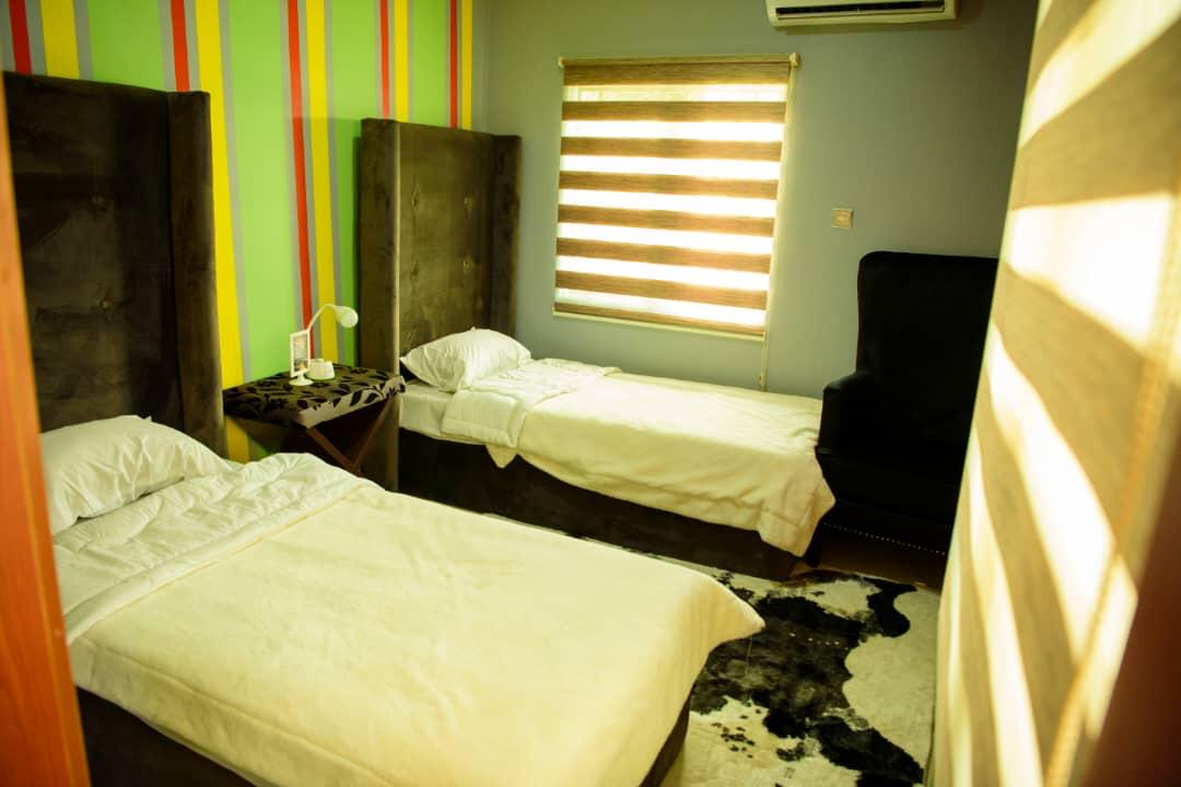 A residential bedroom with a comfortable bed, seating and warm natural light